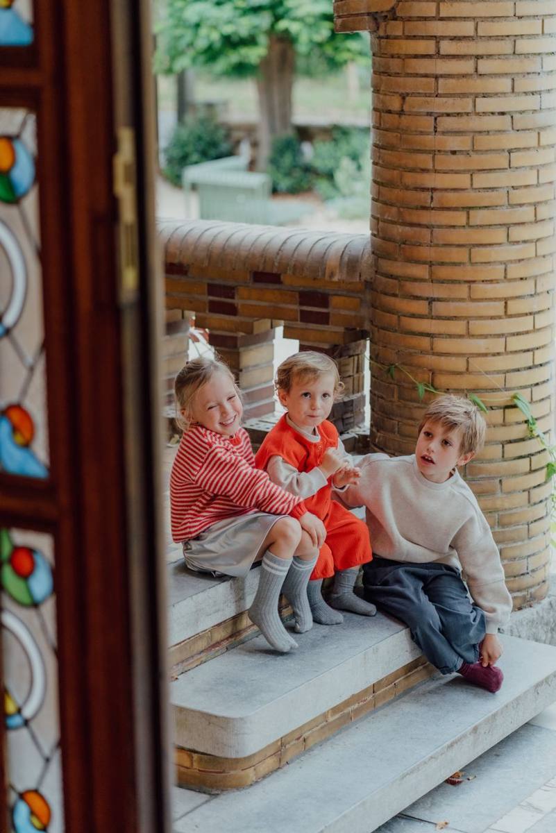 Drie kinderen op de trappen van MOMENT, gezien door de glas-in-loodsdeur