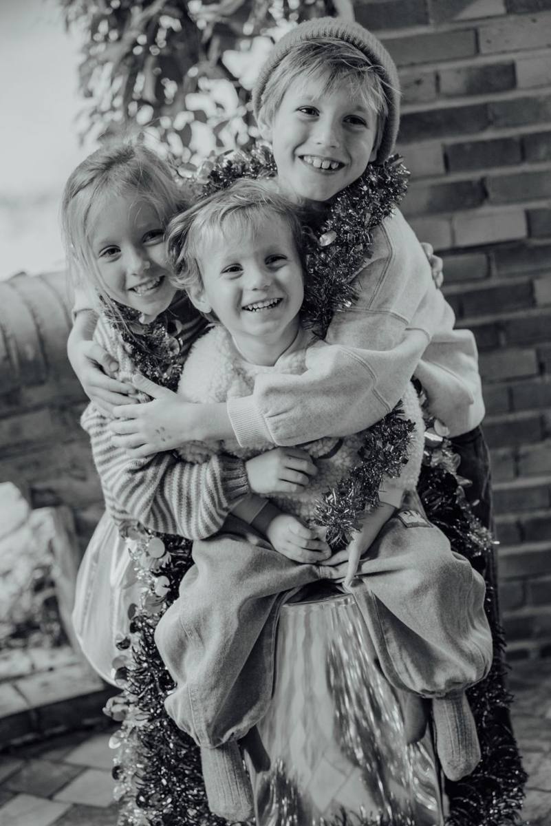 Drie kinderen knuffelen elkaar, zwart-wit