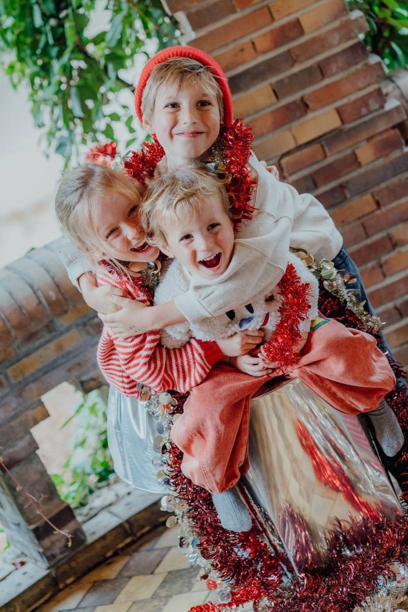 Drie kinderen knuffelen elkaar tussen rode slingers