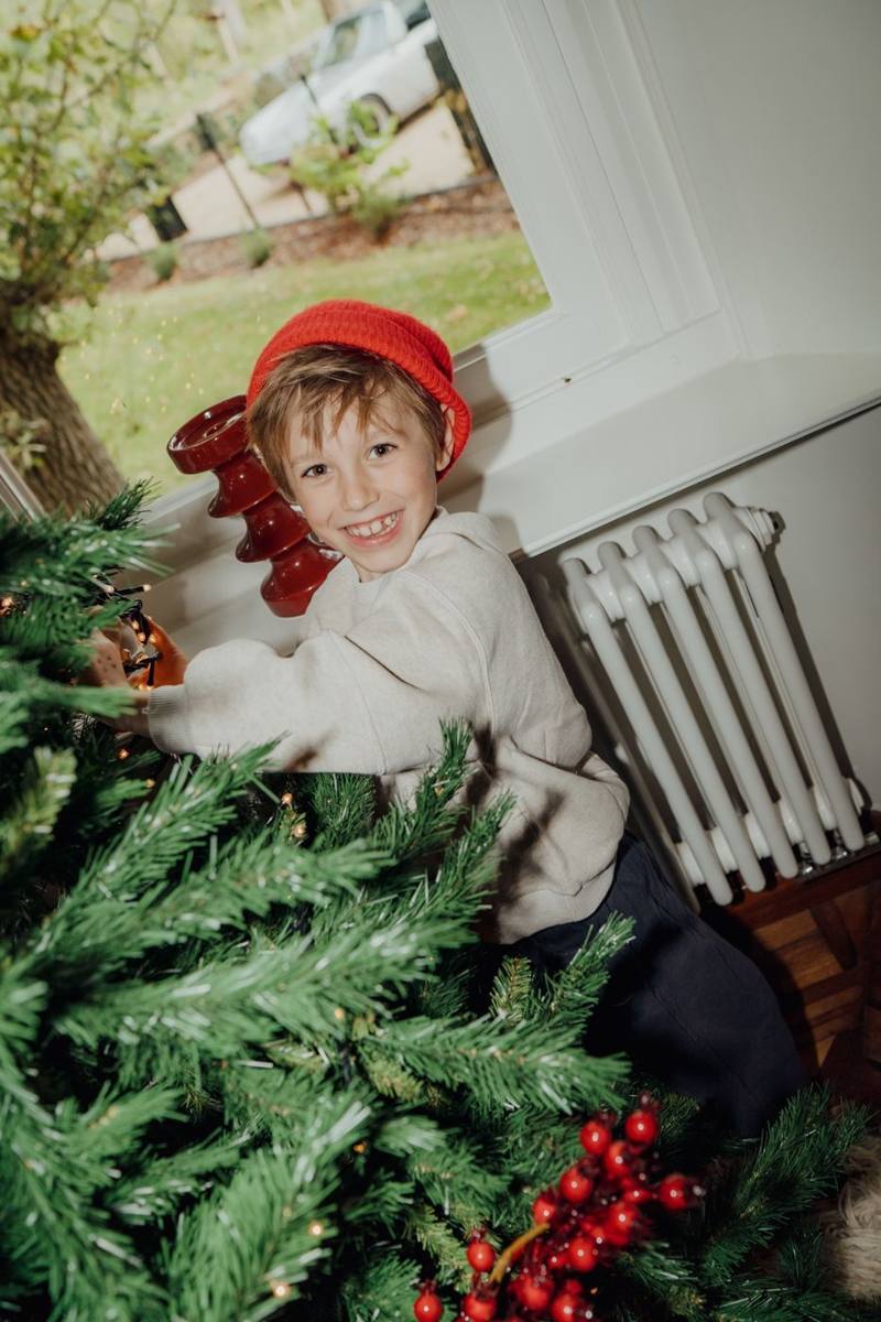 Lachende jongen met rode muts bij de kerstboom